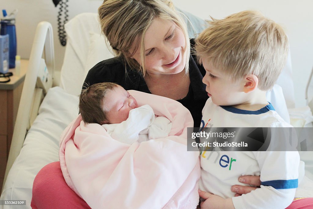 Mother Holding Newborn Baby and Toddler in Hospital