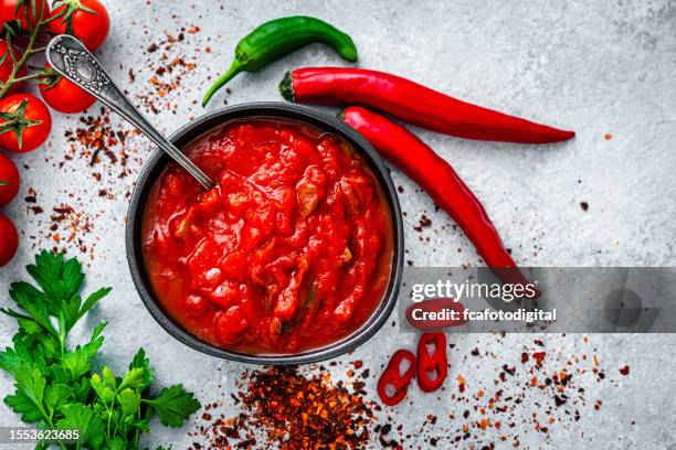 rote, scharfe chilisauce mit zutaten, die von oben auf grauen tisch geschossen werden - chili schote stock-fotos und bilder