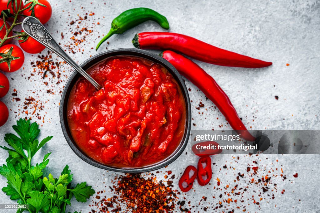 Red hot chili sauce with ingredients shot from above on gray table