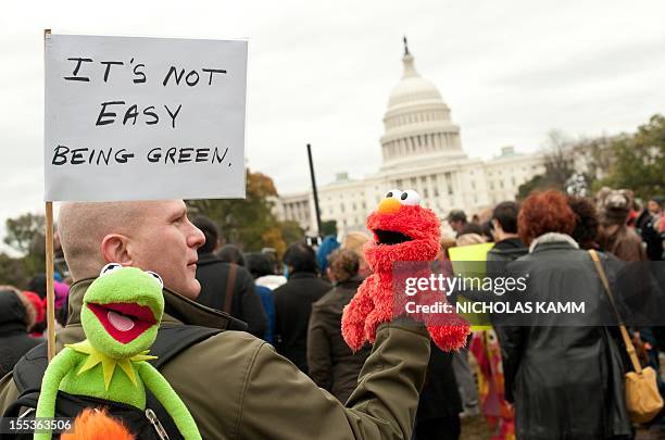 Man carrying puppets of Sesame Street characters Elmo and Kermit holds a sign in front of the Capitol during the "Million Puppet March" in support of...