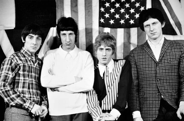 Group portrait of English rock band The Who, standing in front of flags wearing mod clothing, London, circa 1966. Keith Moon, Pete Townshend, Roger...