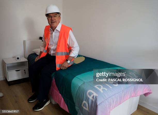 President of the International Olympic Committee Thomas Bach sits on a bed as he visits the Athletes village of the 2024 Summer Olympics in the Paris...