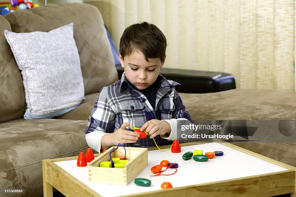 Autista niño jugando con colorido microesferas de madera