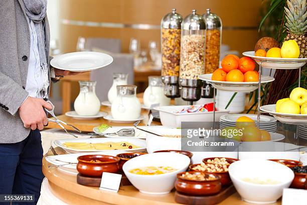 man selecting his meal from a breakfast buffet - buffet stockfoto's en -beelden
