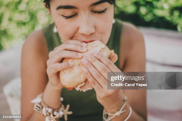 young woman enjoys a serrano ham sandwich outdoors - sandwich photos et images de collection