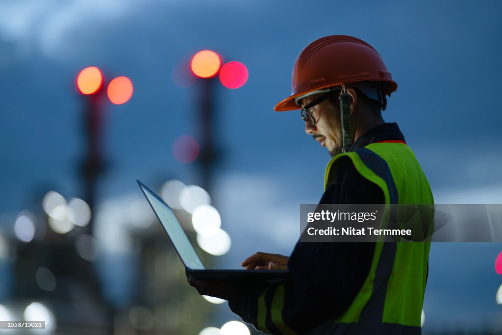 Boosting Key Front-line Operations Through Digitization to Driving Sustainability in Oil and Gas Industry. Side view of Engineer working over a laptop computer to analyze insights related to the production of energy in field operation.