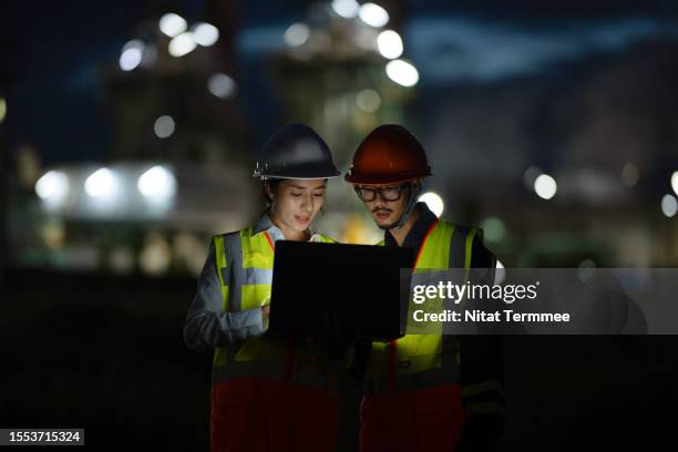 develop and research energy technology to enhancing energy production to support energy supply chain. dedicated engineers working until late hours are discussing over a laptop computer in field operation in the oil and gas industry. - site reliability engineering stock pictures, royalty-free photos & images