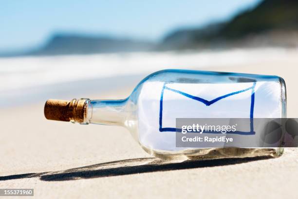 umschlag e-mail-symbol nachricht in der flasche am strand von leeren - flaschenpost stock-fotos und bilder