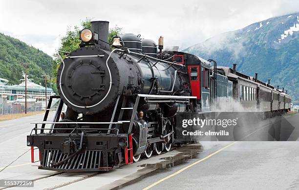 steam train driving down tracks in skagway, alaska  - steam train stock pictures, royalty-free photos & images