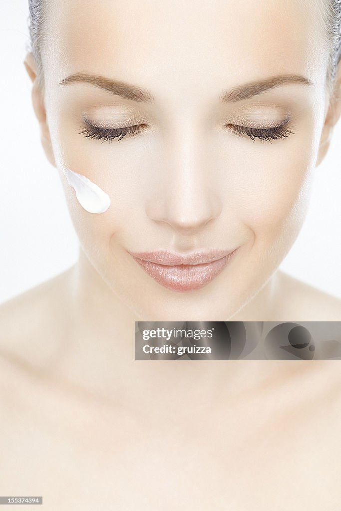 Close-up of a beautiful woman with cream on her face