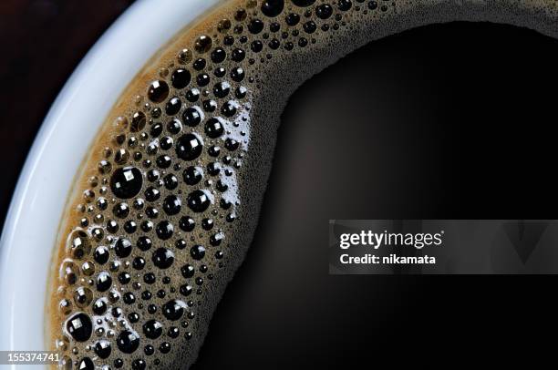 a closeup shot of a cup of black coffee with tiny bubbles - black coffee stock pictures, royalty-free photos & images