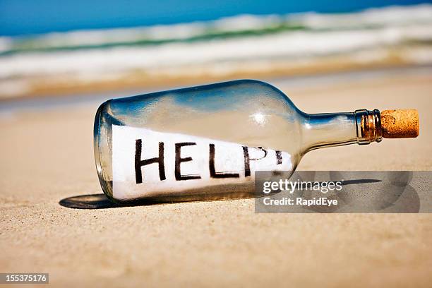 help says frantic message in bottle on deserted beach - message in a bottle stock pictures, royalty-free photos & images