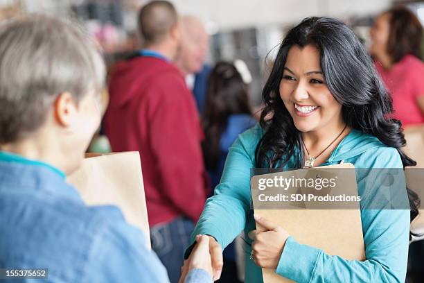 female volunteer greeting woman at donation facility - maatschappelijke dienstverlening stockfoto's en -beelden