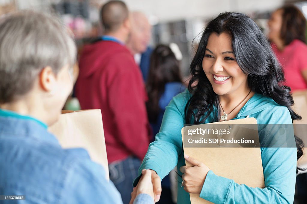 Female volunteer greeting woman at donation facility