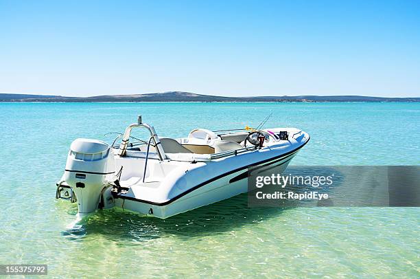 bateau amarré dans les eaux peu profondes du lagon turquoise - bateau à moteur photos et images de collection