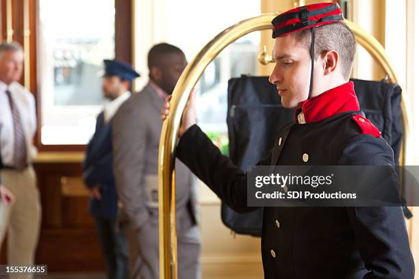 fattorino d'albergo con carrello bagagli in attesa per gli ospiti dell'hotel - bellhop foto e immagini stock