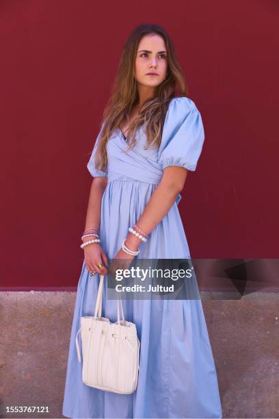 young white girl in blue dress poses on red wall - fashion long dress stock pictures, royalty-free photos & images