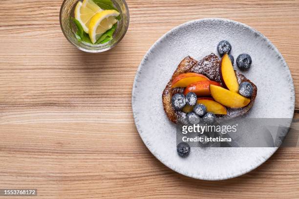 french toast with peach, blueberries.  breakfast, glass of fresh water with lemon and mint leaves - icing sugar stock pictures, royalty-free photos & images