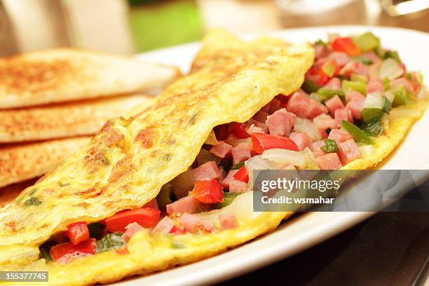 a folded egg omelets filled with chopped ham and vegetables - omelette stock pictures, royalty-free photos & images