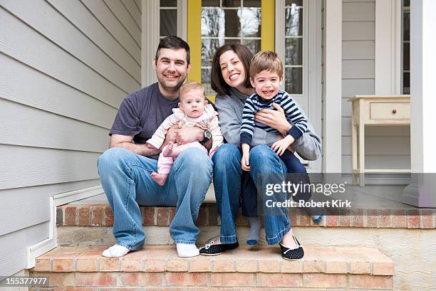 candid portrait of family sitting on front porch stairs - family smiling at front door stock pictures, royalty-free photos & images