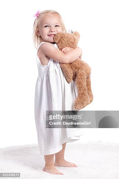glückliches kleines mädchen im weißen kleid umarmen jagdtrophäe - teddybär freisteller stock-fotos und bilder