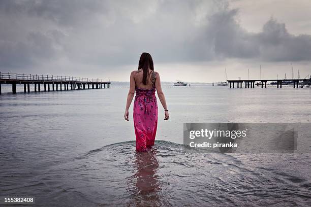 woman walking in the sea on rainy day - grey dress stock pictures, royalty-free photos & images