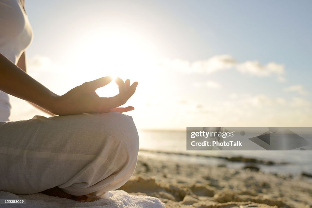 Frau sitzt am Strand mit Yoga Lotus Position