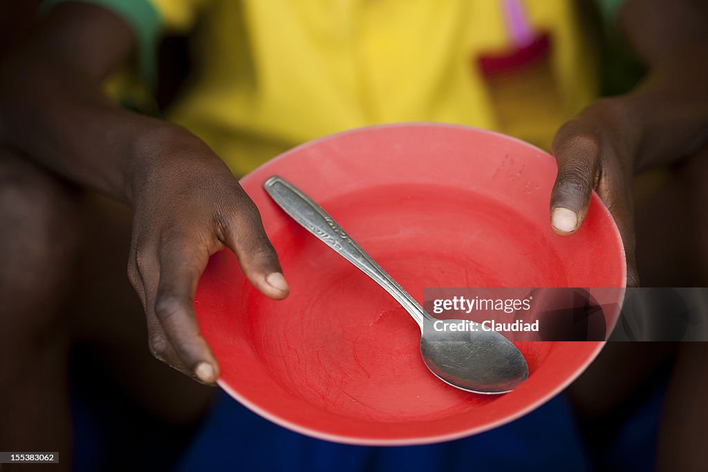 African child holds empty plate