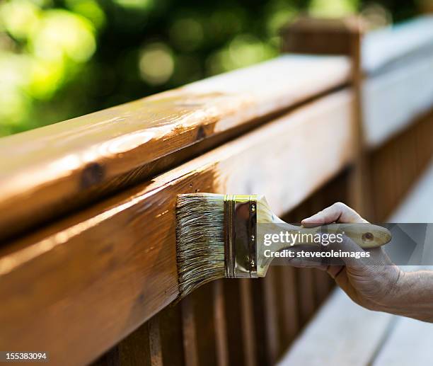 male carpenter applying varnish to wooden furniture. - pressure treated wood stock pictures, royalty-free photos & images