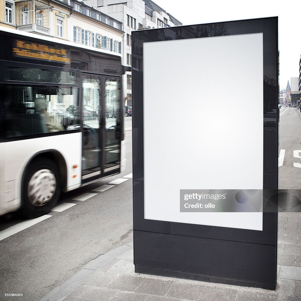 Blank advertising billboard on city street, bus passes