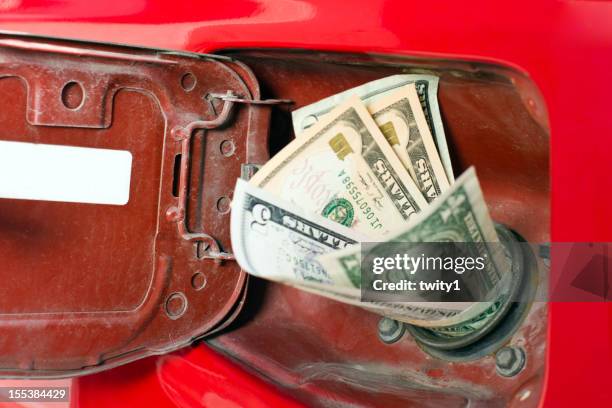 money in the chute of a gas representing high gas prices - fuel price stockfoto's en -beelden