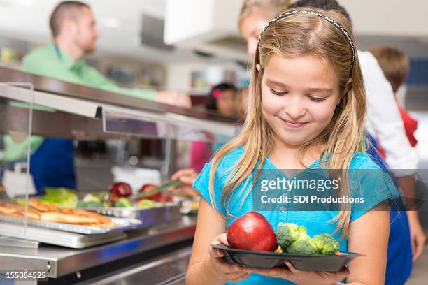 happy little girl making healthy choices in school cafeteria - school lunch stock pictures, royalty-free photos & images