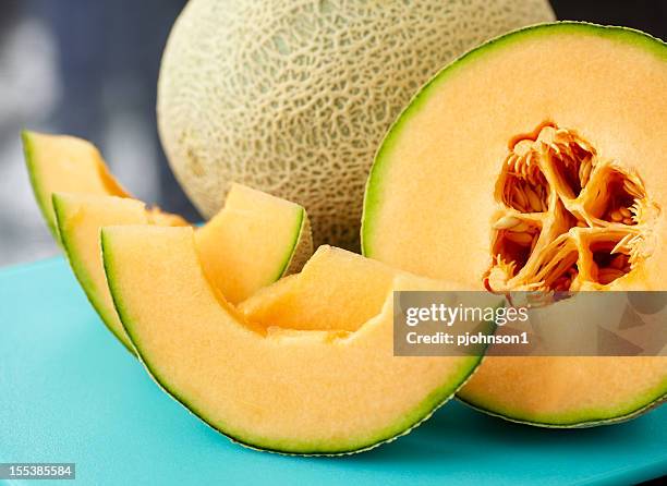 a close up of a sliced cantaloupe on a blue table - cantaloupe melon stock pictures, royalty-free photos & images