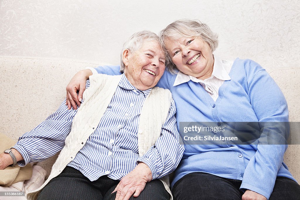 Mature daughter and senior mother on sofa