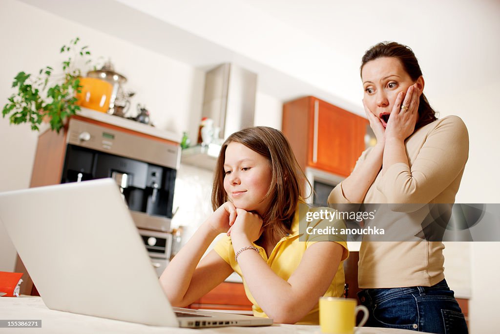 Feliz madre con hija usando una computadora portátil en su hogar