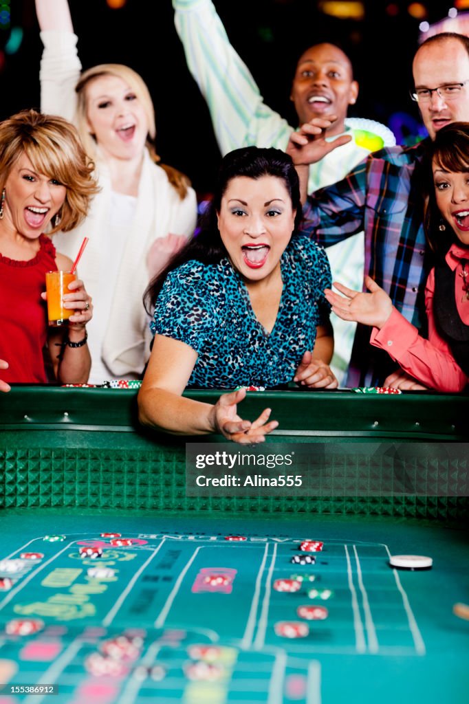 Large group of happy diverse people at the craps table