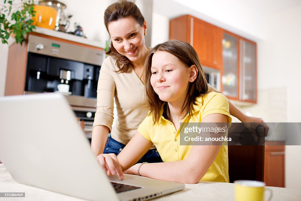 Feliz madre con hija usando una computadora portátil en su hogar