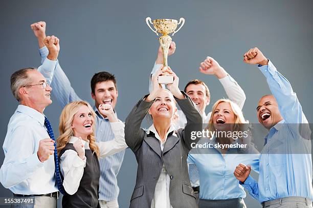 cheerful group of businesspeople winning the cup with hands up. - holding trophy stock pictures, royalty-free photos & images