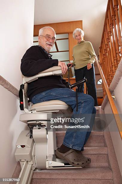 joyeux les retraités avec stairlift: maison de retraite - ascenseur interieur photos et images de collection
