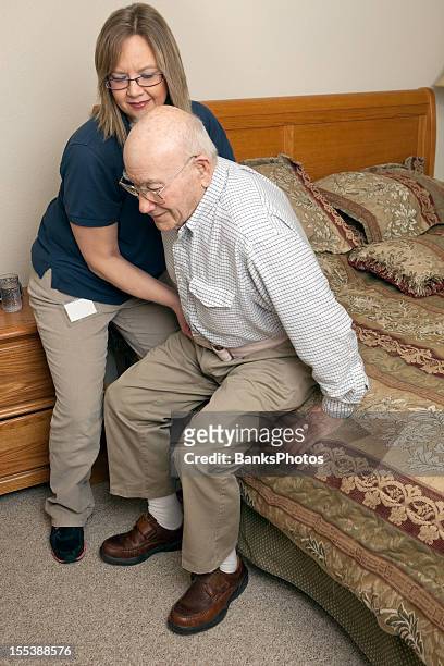 home healthcare worker using gait belt to assist patient - ceintuur stockfoto's en -beelden