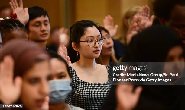 Melanie Asilo, from the Philippines, raises her hand as she takes the Oath of Allegiance during a naturalization ceremony in the Rotunda of the State...