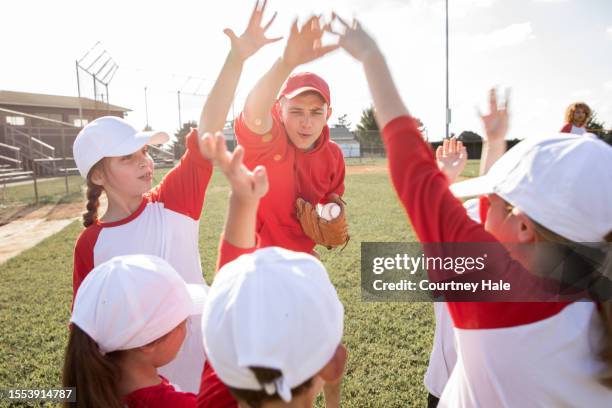 coach leads huddle with team of little league baseball players on field - baseball team stock pictures, royalty-free photos & images