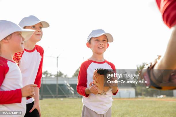 little boy talks with coach and teammates during little league baseball game - baseball huddle stock pictures, royalty-free photos & images