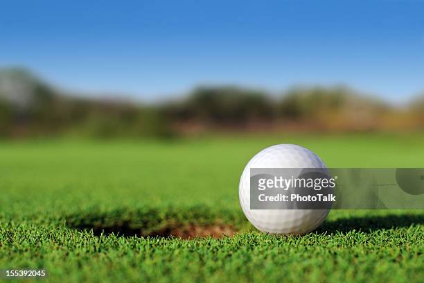 ground level close up of golf ball close to hole - golf ball stock pictures, royalty-free photos & images
