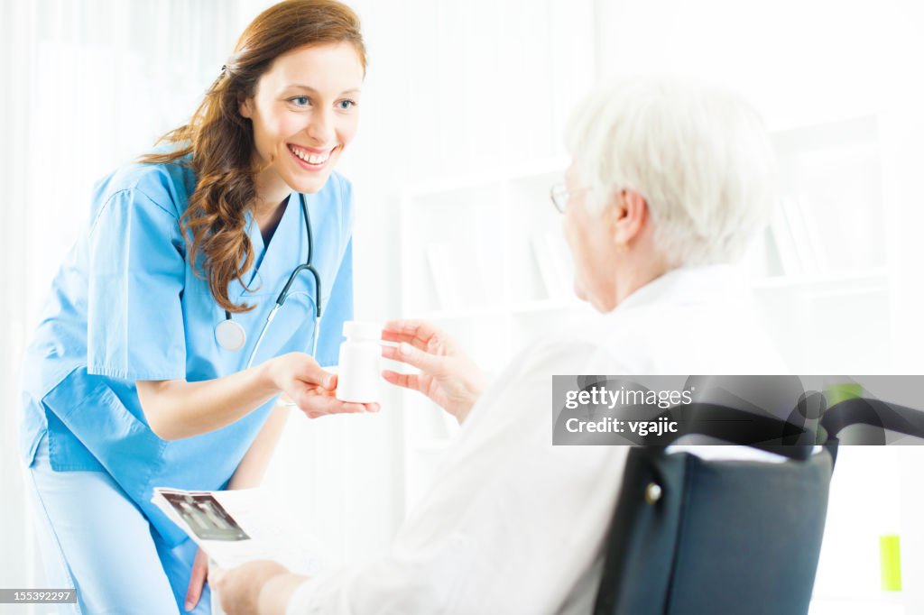 Médico dar um medicamento a mulher idosa.