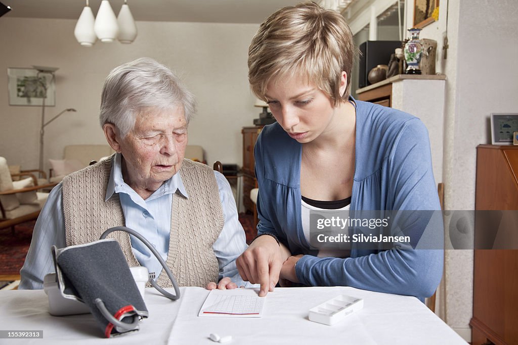 Fürsorgliche erklären Blutdruck und Medizin, senior Frau