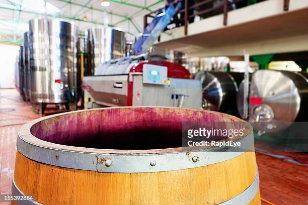 grape-stained wine barrel with modern winery equipment in background - industrial hose stockfoto's en -beelden