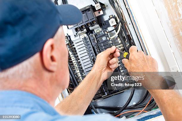 electrician doing electrical work in breaker box - elektricien stockfoto's en -beelden