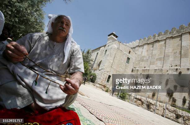 Palestinian Muslim worshipper holds his prayer beads as he sits on a straw mat in the courtyard of the Ibrahimi mosque, a holy site to both Muslims...