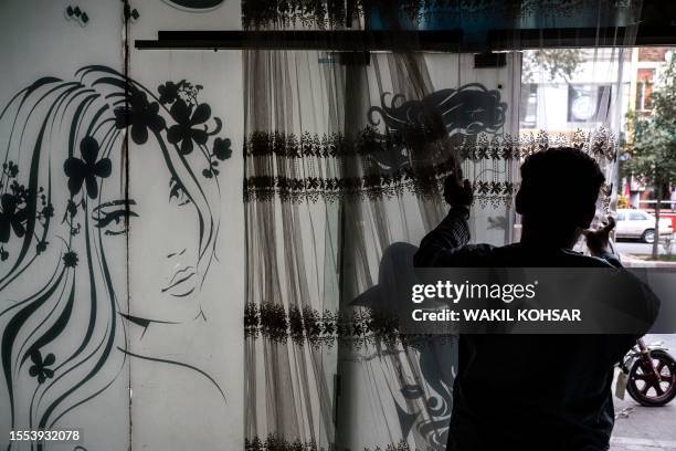 An afghan man remove curtains inside a beauty parlour in Kabul on July 25, 2023. Afghanistan's Taliban authorities have ordered beauty parlours...